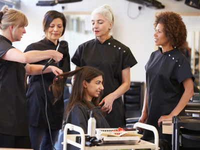 Profissional cabeleireiro(a) cortando e modelando cabelo em salão de beleza.
