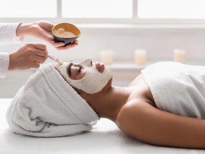 Imagem mostrando profissional realizando limpeza de pele em cliente com produtos e equipamentos específicos em clínica estética.